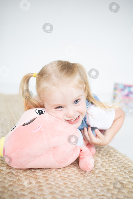 Скачать Счастливая девочка с мягкой игрушкой на белом фоне фотосток Ozero