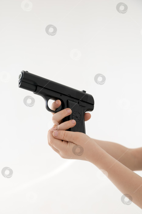 Скачать Крупным планом мужская рука, держащая черный пластиковый игрушечный пистолет на белом фоне.игрушечный пистолет в руке НА БЕЛОМ ФОНЕ фотосток Ozero