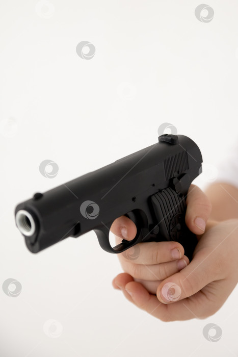 Скачать Крупным планом мужская рука, держащая черный пластиковый игрушечный пистолет на белом фоне.игрушечный пистолет в руке НА БЕЛОМ ФОНЕ фотосток Ozero