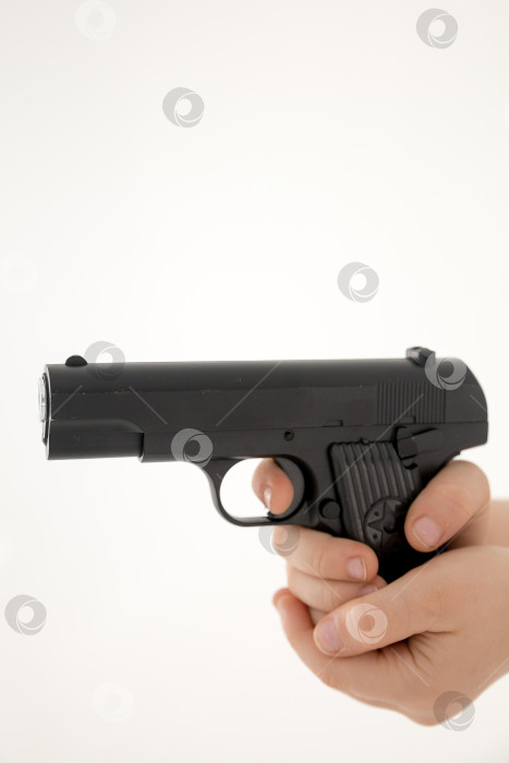 Скачать Крупным планом мужская рука, держащая черный пластиковый игрушечный пистолет на белом фоне.игрушечный пистолет в руке НА БЕЛОМ ФОНЕ фотосток Ozero