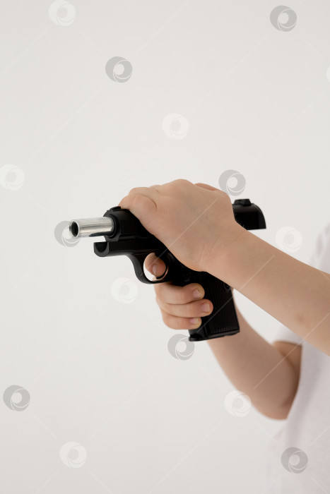 Скачать Крупным планом мужская рука, держащая черный пластиковый игрушечный пистолет на белом фоне.игрушечный пистолет в руке НА БЕЛОМ ФОНЕ фотосток Ozero