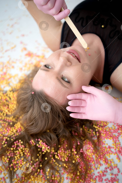 Скачать Женщина лежит на полу. воск для депиляции на волосах. Концепция ухода за собой фотосток Ozero