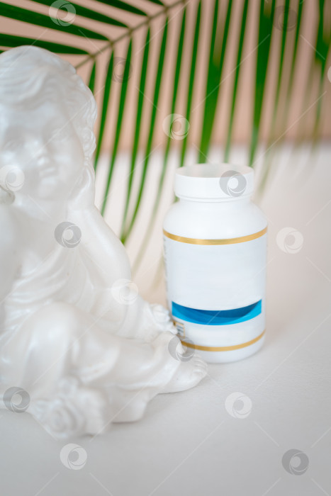 Скачать баночка с витаминами в белом флаконе стоит на столе на фоне зеленых листьев. Биологически активные добавки. омега-6, омега-9, витамины А, Е, D, витамин D3, фотосток Ozero