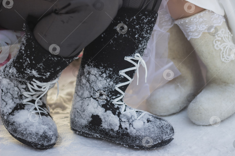 Скачать Зимняя обувь: валенки - крупным планом. Человек зимой на улице, в снегу, в валенках.Две пары валенок. Теплые валенки из шерсти животных. Традиционная обувь. Символ холода, мороза. фотосток Ozero