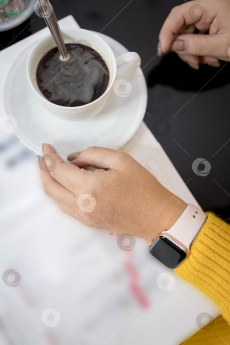 Скачать Чашка теплого кофе в руках человека в желтом свитере, стоящего утром на уютном столике. Руки человека в желтом свитере с чашкой кофе лежат на столе. фотосток Ozero