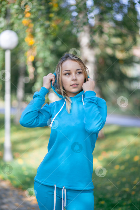 Скачать Улыбающаяся девушка в синем спортивном костюме на улице смотрит в камеру фотосток Ozero