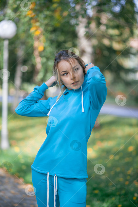 Скачать Улыбающаяся девушка в синем спортивном костюме на улице смотрит в камеру фотосток Ozero