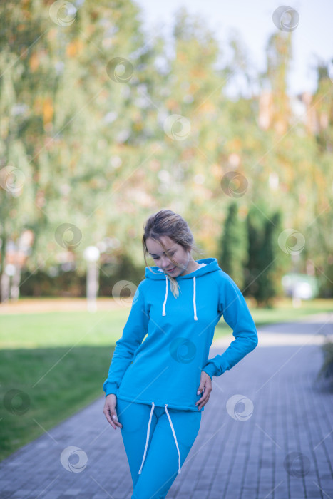 Скачать Улыбающаяся девушка в синем спортивном костюме на улице смотрит в камеру фотосток Ozero