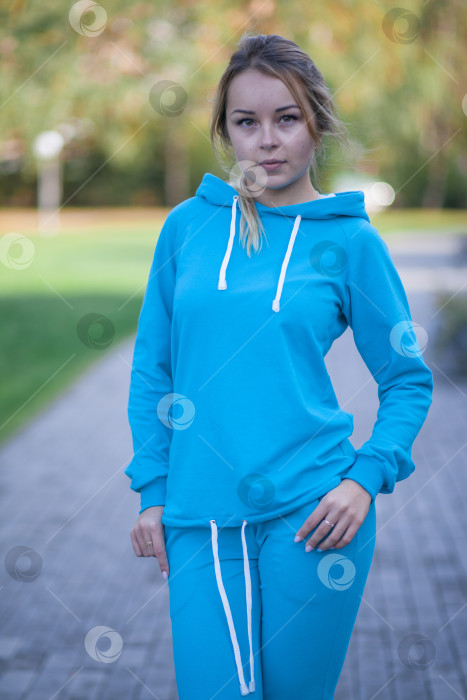 Скачать Улыбающаяся девушка в синем спортивном костюме на улице смотрит в камеру фотосток Ozero