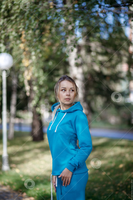 Скачать Улыбающаяся девушка в синем спортивном костюме на улице смотрит в камеру фотосток Ozero