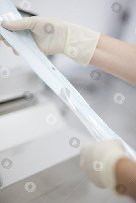 Скачать Автоклавное устройство для стерилизации медицинских изделий, с помощью которых используются инструменты. Рука рабочего вводит инструменты внутрь. фотосток Ozero