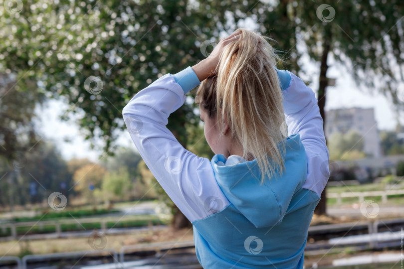 Скачать Молодая девушка в спортивной синей толстовке с капюшоном на открытом воздухе фотосток Ozero