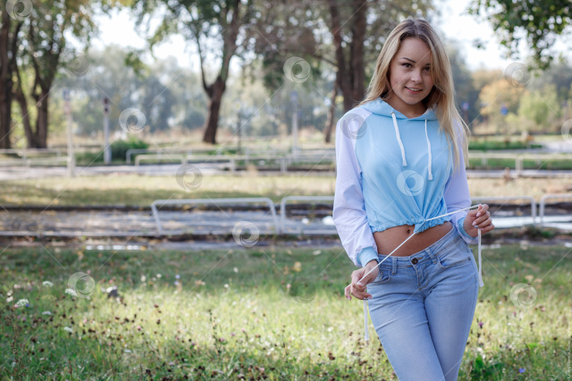 Скачать Молодая девушка в спортивной синей толстовке с капюшоном на открытом воздухе фотосток Ozero