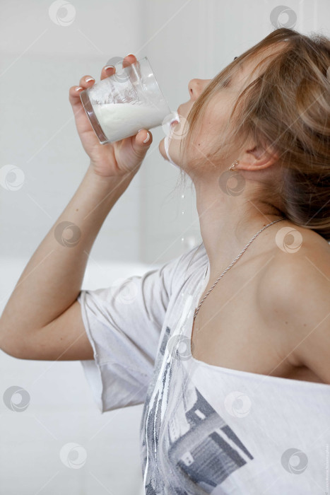 Скачать Женщина пьет молоко и проливает его себе на шею фотосток Ozero
