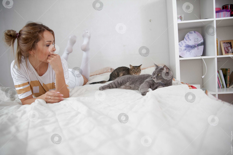 Скачать Женщина и кошка лежат на кровати на белом покрывале фотосток Ozero