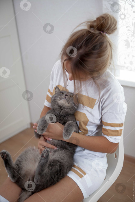 Скачать Женщина и кошка лежат на кровати на белом покрывале фотосток Ozero