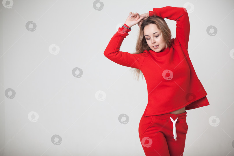 Скачать Женщина в красном спортивном костюме на белом фоне смотрит в камеру фотосток Ozero