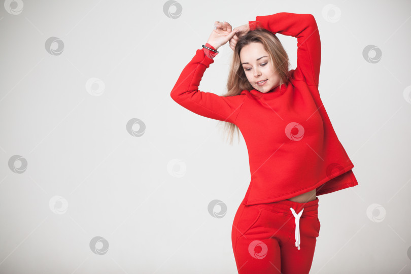 Скачать Женщина в красном спортивном костюме на белом фоне смотрит в камеру фотосток Ozero