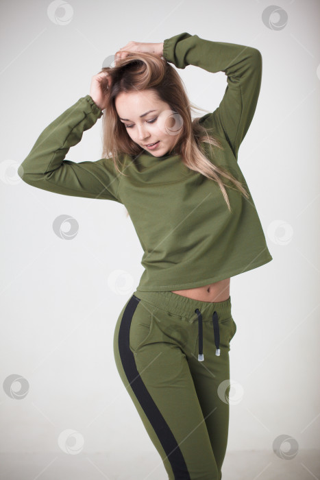 Скачать Женщина в зеленом спортивном костюме на белом фоне смотрит в камеру фотосток Ozero