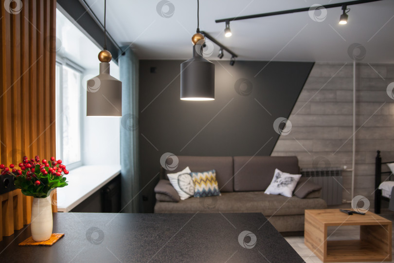 Скачать Серый диван с одеялом, подушкой, деревянным журнальным столиком и растением на деревянном полу в минималистском интерьере. фотосток Ozero