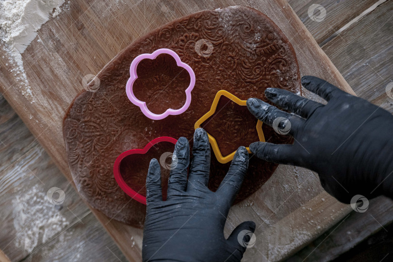 Скачать Сырое пасхальное печенье и формочки для печенья на бумаге для выпечки, вид сверху. Фотографии высокого качества. руки кондитера в перчатках фотосток Ozero