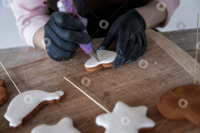 Скачать Сырое пасхальное печенье и формочки для печенья на бумаге для выпечки, вид сверху. Фотографии высокого качества. руки кондитера в перчатках фотосток Ozero