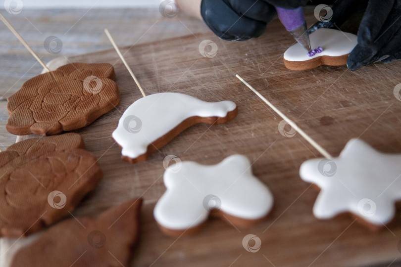 Скачать Сырое пасхальное печенье и формочки для печенья на бумаге для выпечки, вид сверху. Фотографии высокого качества. руки кондитера в перчатках фотосток Ozero