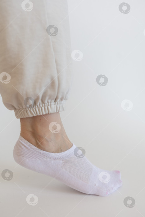 Скачать Женская ножка в белом носке на белом фоне фотосток Ozero