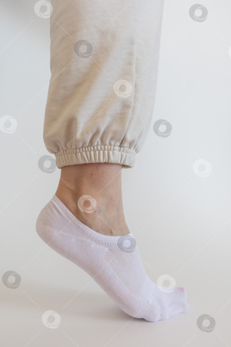 Скачать Женская ножка в белом носке на белом фоне фотосток Ozero