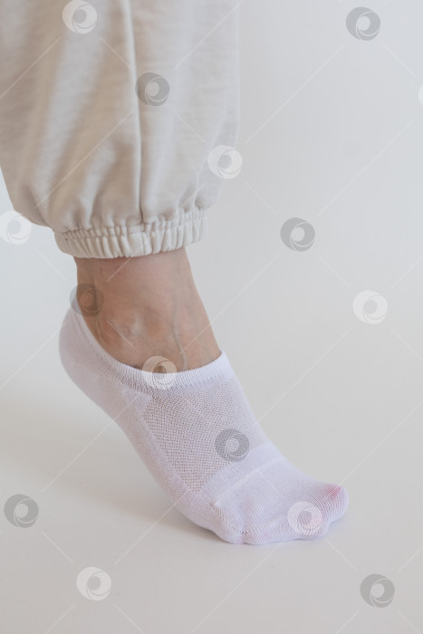 Скачать Женская ножка в белом носке на белом фоне фотосток Ozero