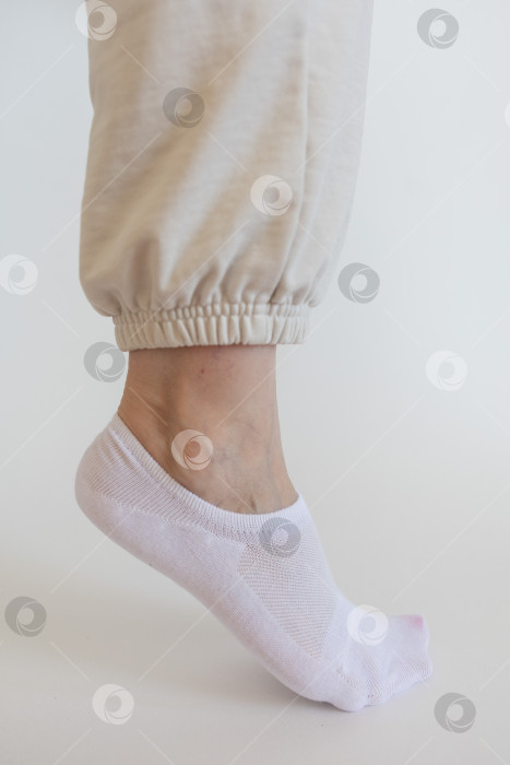 Скачать Женская ножка в белом носке на белом фоне фотосток Ozero