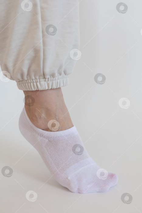 Скачать Женская ножка в белом носке на белом фоне фотосток Ozero