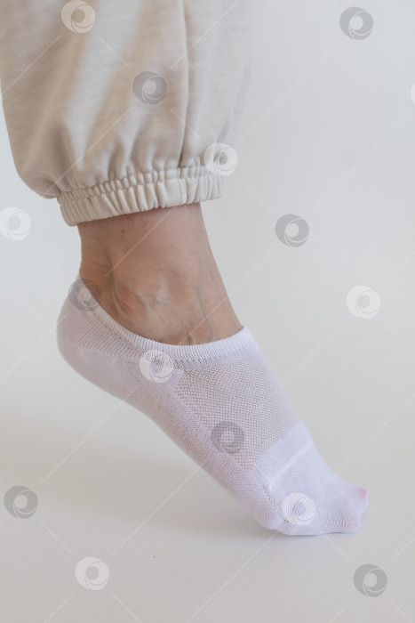 Скачать Женская ножка в белом носке на белом фоне фотосток Ozero