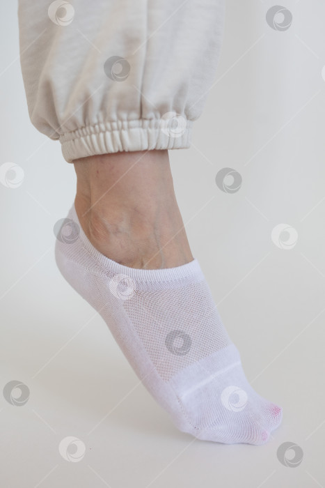 Скачать Женская ножка в белом носке на белом фоне фотосток Ozero