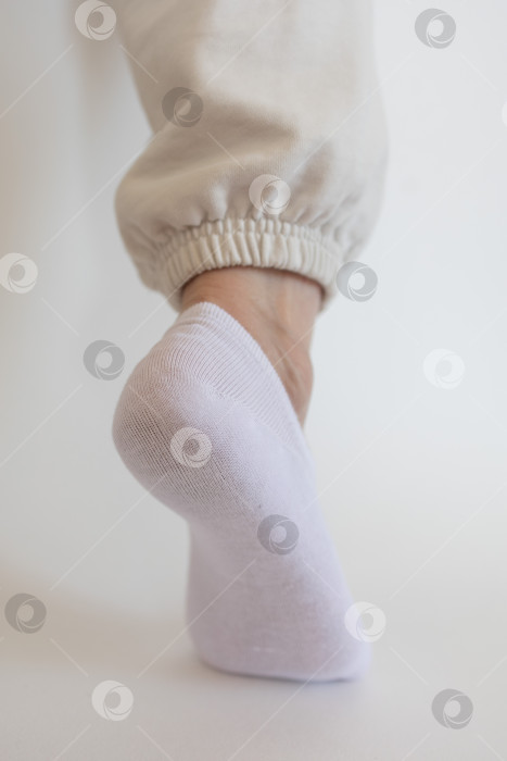 Скачать Женская ножка в белом носке на белом фоне фотосток Ozero