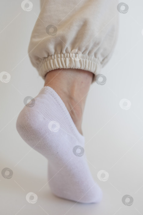 Скачать Женская ножка в белом носке на белом фоне фотосток Ozero