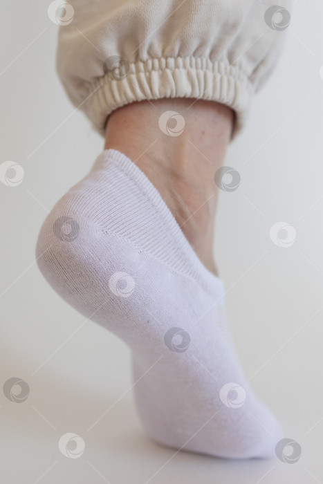 Скачать Женская ножка в белом носке на белом фоне фотосток Ozero
