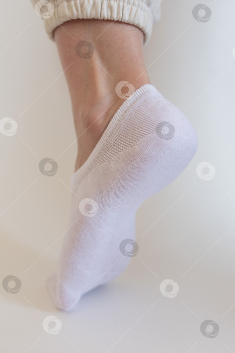 Скачать Женская ножка в белом носке на белом фоне фотосток Ozero