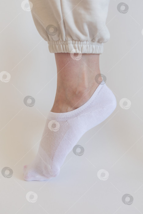 Скачать Женская ножка в белом носке на белом фоне фотосток Ozero