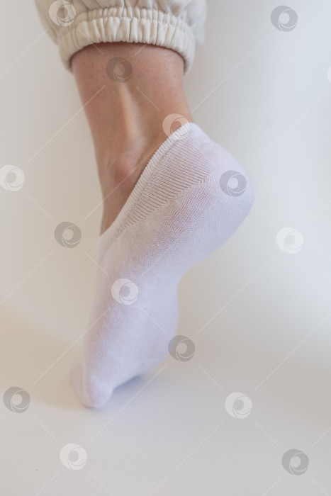 Скачать Женская ножка в белом носке на белом фоне фотосток Ozero
