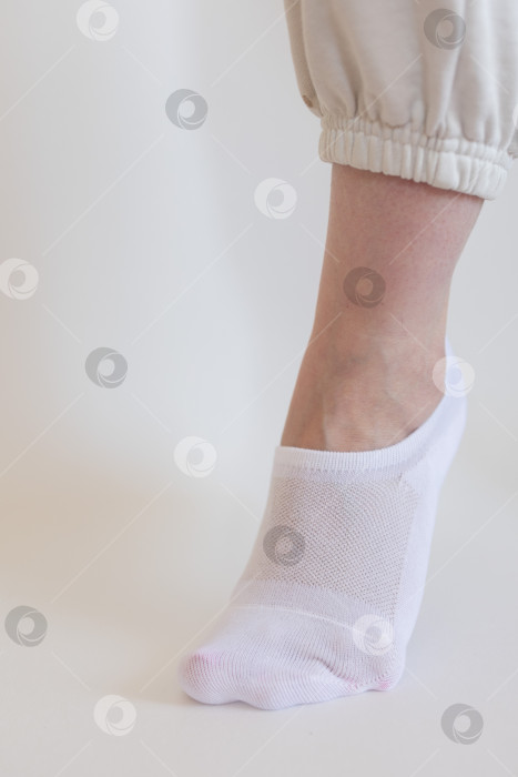 Скачать Женская ножка в белом носке на белом фоне фотосток Ozero