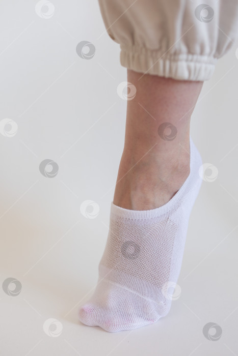 Скачать Женская ножка в белом носке на белом фоне фотосток Ozero