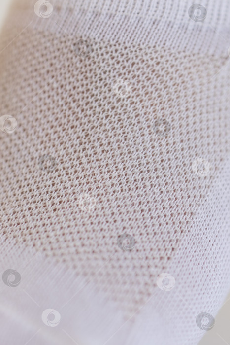 Скачать Женская ножка крупным планом в белом носке на белом фоне.Ткацкая ткань крупным планом. фотосток Ozero