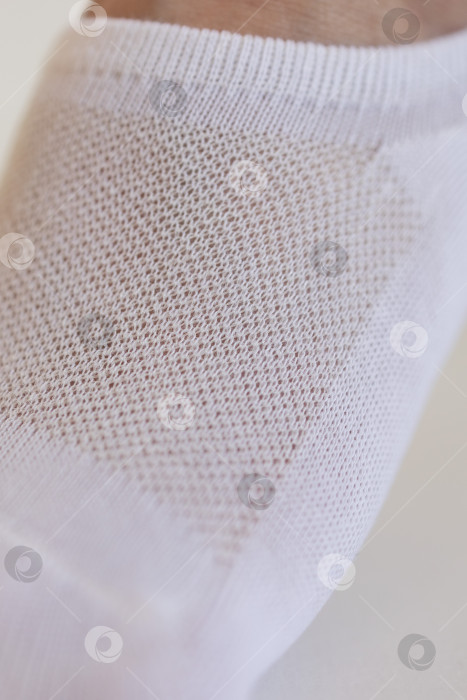 Скачать Женская ножка крупным планом в белом носке на белом фоне.Ткацкая ткань крупным планом. фотосток Ozero