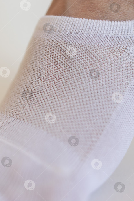 Скачать Женская ножка крупным планом в белом носке на белом фоне.Ткацкая ткань крупным планом. фотосток Ozero