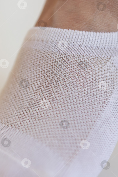 Скачать Женская ножка крупным планом в белом носке на белом фоне.Ткацкая ткань крупным планом. фотосток Ozero