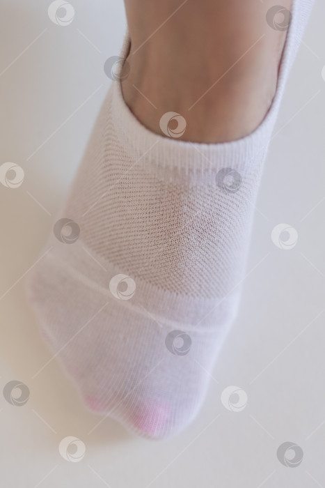 Скачать Женская ножка крупным планом в белом носке на белом фоне.Ткацкая ткань крупным планом. фотосток Ozero