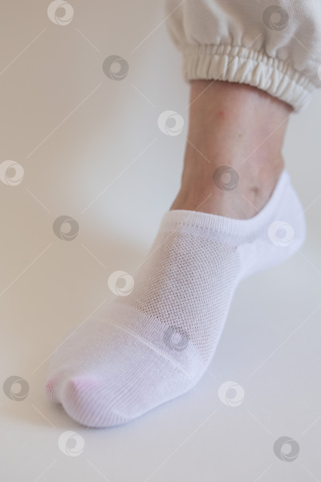 Скачать Женская ножка в белом носке на белом фоне фотосток Ozero