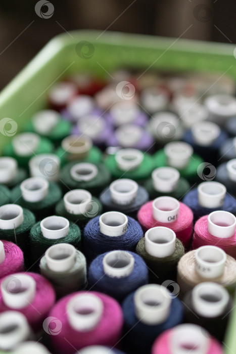 Скачать Большая группа разноцветных катушек с нитками для шитья на рабочем месте в небольшом ателье. вид сверху фотосток Ozero