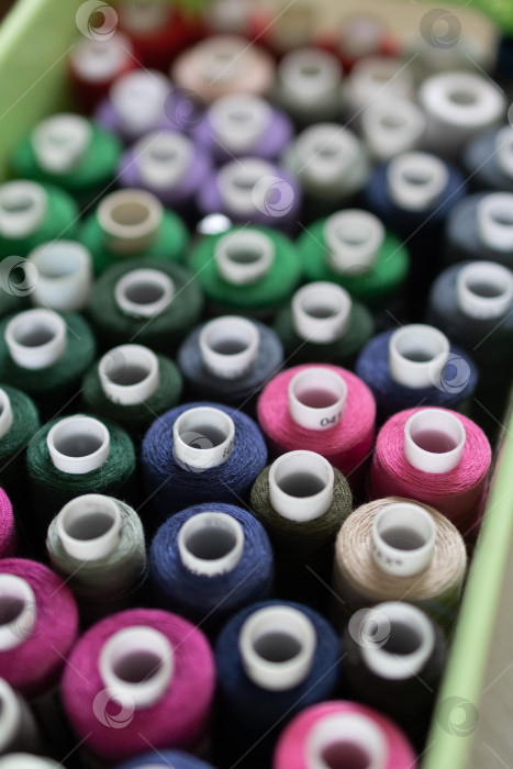 Скачать Большая группа разноцветных катушек с нитками для шитья на рабочем месте в небольшом ателье. вид сверху фотосток Ozero